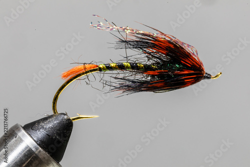 Orange hilton style fly on a tying vice ready to take fishing for steelhead