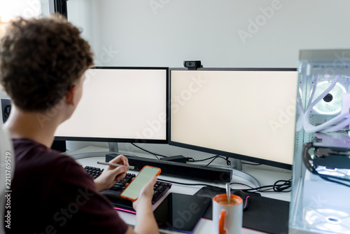 Young man using AI tools at dual monitor computer