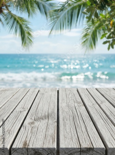 A beautifully weathered wooden picnic tabletop showcases a stunning blurred tropical ocean waves bokeh background perfect for travel, resort, and vacation marketing presentations.