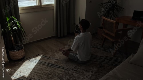 Remote worker taking a mindful meditation break at home, sitting quietly beside a work desk and laptop to reset mentally, reduce stress and regain focus during the working day