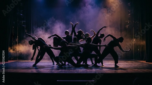 Contemporary dancers performing synchronized choreography on a smoky stage under dramatic theatrical lighting