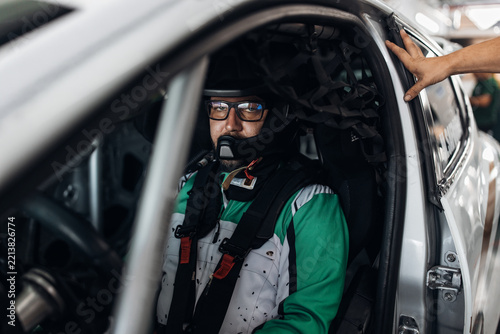 A focused driver wearing glasses inside the car before the race close up