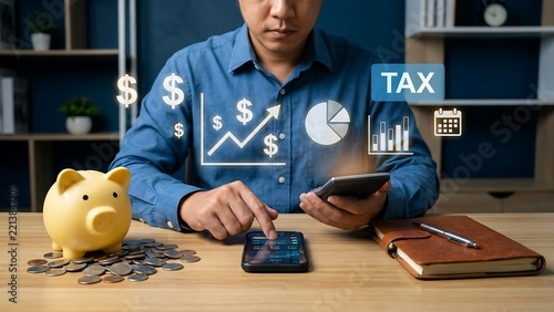 A person in a blue shirt using a smartphone at a desk with a yellow piggy bank, coins, a notebook, and floating digital financial icons and tax