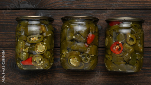 Fotografie Three Jars of Pickled Jalapenos on Wooden Surface for Spicy Culinary Creations