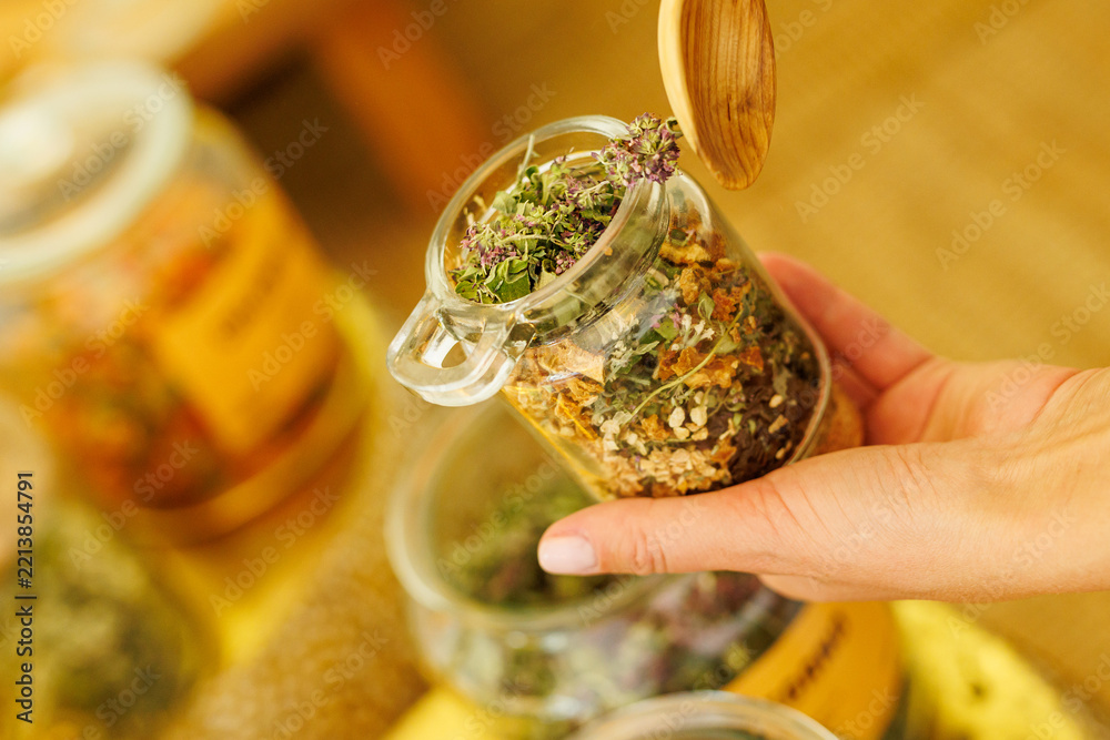 Fototapeta premium Hand holding glass jar with dried herbal tea mixture