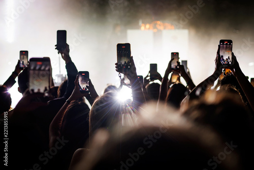 Concert crowd raising hands and filming with smartphones