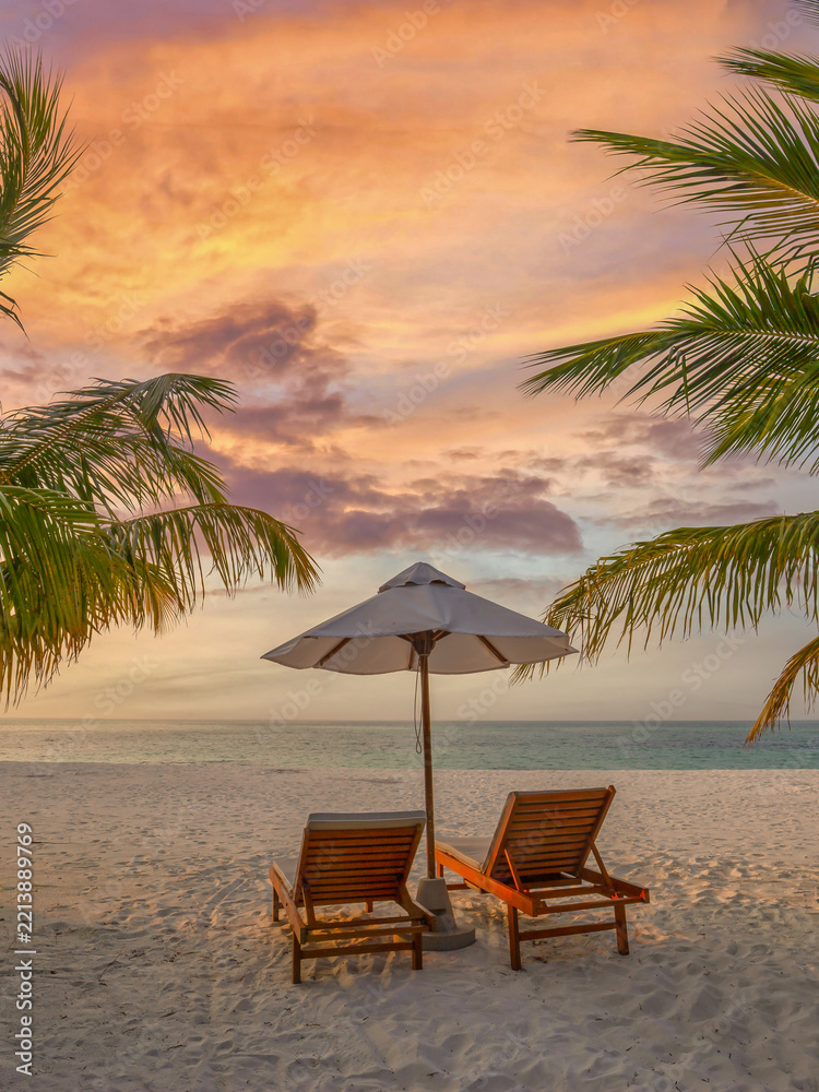 Fototapeta premium Tranquil sunset tropical beach sunbeds white umbrella coconut palm trees sandy shore sky ocean summer. Perfect couple vacation travel vertical scene. Relaxing holiday paradise leisure coastal escape