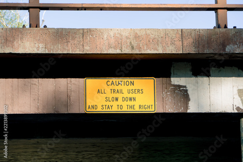 Trail caution sign beneath a bridge