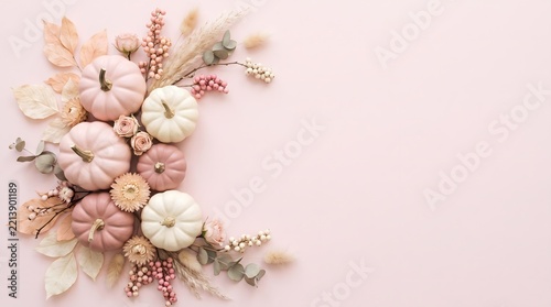 Autumn background with decorative pastel pumpkins and dried flowers on a soft pink surface