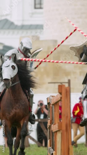 Powerful strike breaks long weapon against armored competitor. Vertical slow motion video captures exact moment splinters fly from smashing pole during epic medieval reenactment event.