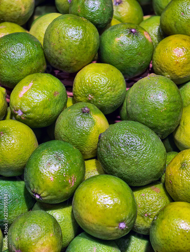 Green limes displayed for sale on a supermarket counter, presenting fresh citrus fruits arranged at a grocery retail display