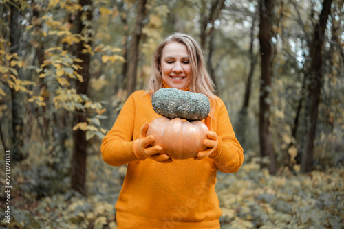 Focused woman examining ripe autumn pumpkin in woods - organic crop inspection concept. Small scale farming and quality harvest check. Female farmer looking at harvested squash.