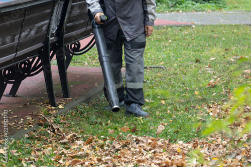 A man, a utility worker, removes leaves from the road with a special device