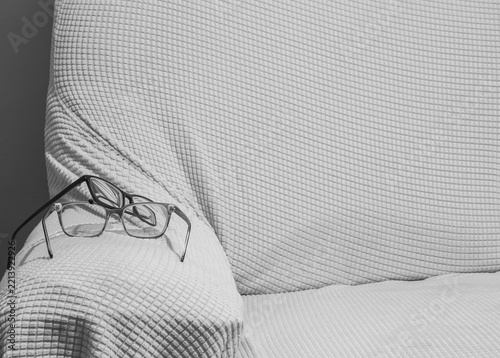 A Pair of Reading Glasses on the Arm of a Textured Fabric Sofa Chair.