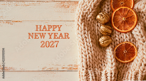 A soft warm arrangement of knitted wool texture, gilded walnuts, and dried orange slices on wood