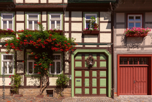 Colorful traditional half-timbered houses with decorative facades, red tiled roofs and flowers along a cobblestone street in Wernigerode, Germany.