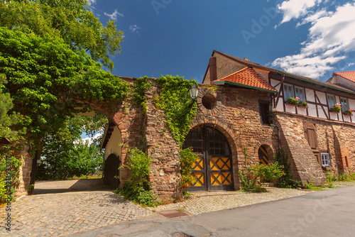 Historic stone buildings with arched gateways, traditional half-timbered architecture and ivy-covered walls in Wernigerode, Germany.