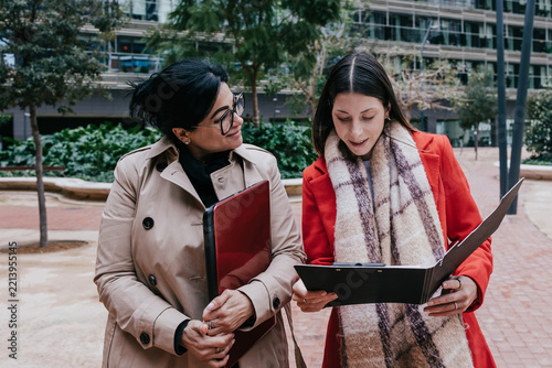 Young Hispanic women teamwork working in the business sector and using laptop outdoors in Public park in businesswoman empowerment concept in urban scene in winter