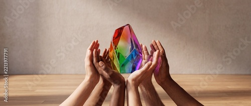 Diverse Group of Hands Representing Different Ethnicities Holding a Vibrant Multi Colored Rainbow Faceted Crystal Metaphor for Unity Inclusion Teamwork and Community Harmony