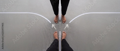 Minimalist overhead view of two people standing at a symbolic crossroads with glowing arrows and paths, representing business decision making, life choices, and strategic career directions.