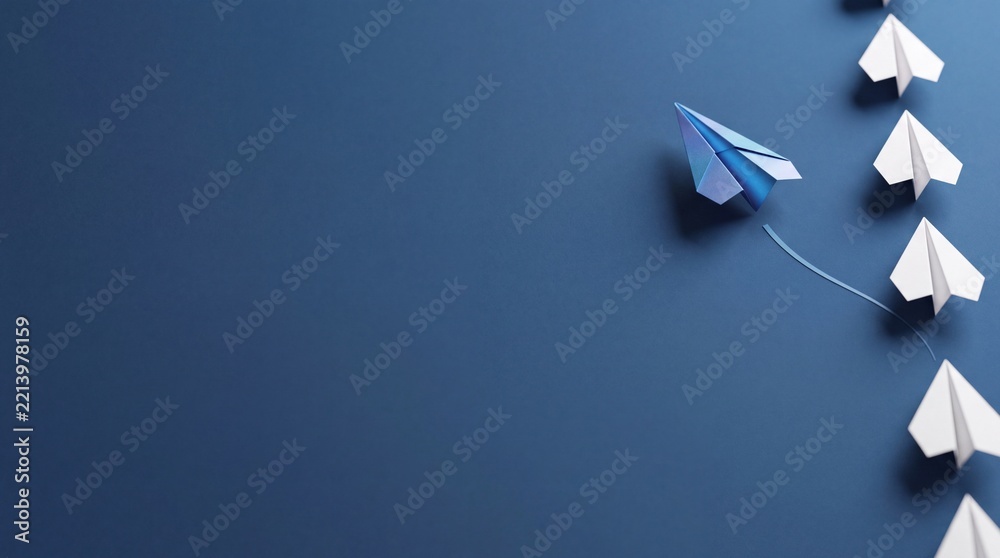 Fototapeta premium A blue paper plane breaking away from a vertical line of white paper planes against a dark blue background with significant negative space on the left, symbolizing leadership and innovation.
