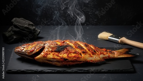 Dramatic Maldivian Fihunu Mas Grilled Whole Reef Fish with Smoke on Dark Slate and Copy Space