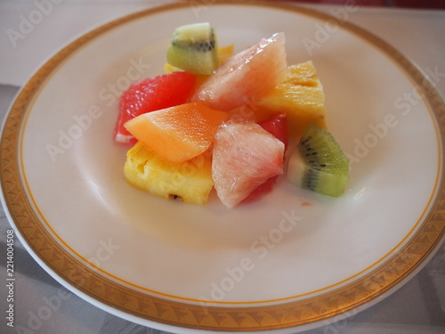 Assorted fresh cut fruits served on a white plate with gold rim