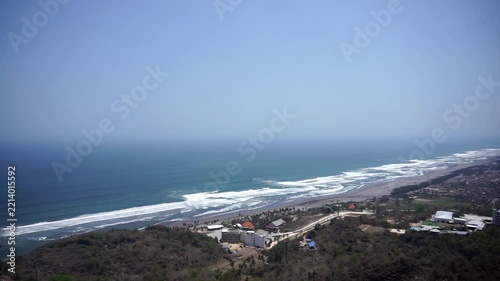 A panoramic view of Java's southern coast and the crashing waves of Parangtritis Beach, captured from the top of the Obelix cliff.