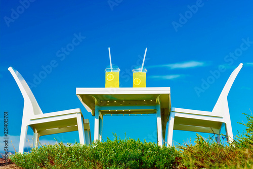Green and blue hills, white terrace seats with lemonade