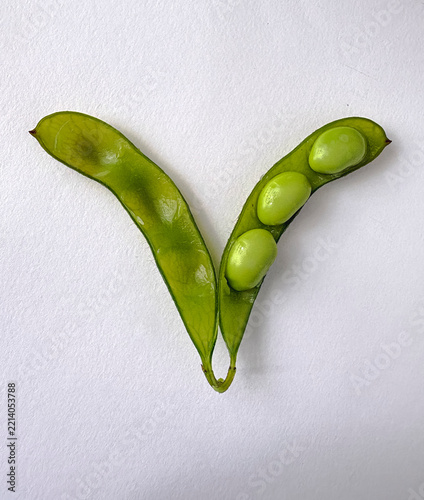 Fresh green edamame nestled in an open pod. Simple white background highlights natural texture. Minimalist composition evokes freshness and growth. Ideal for healthy eating, organic food