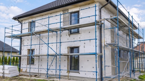 Two Story Modern Residential House Undergoing External Thermal Insulation with Scaffolding, Renovation Construction Project for Improving Energy Efficiency
