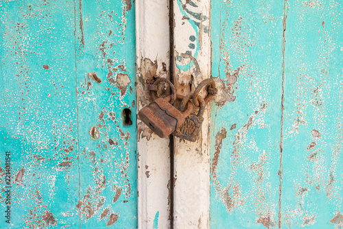 Detail of rustic weathered door with peeling aquamarine paint