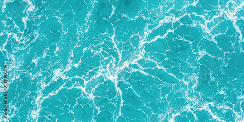 The turbulent turquoise sea water creates a mesmerizing pattern of white foam and wave crests, offering a visually stunning and abstract depiction of nature's raw power and beauty.
