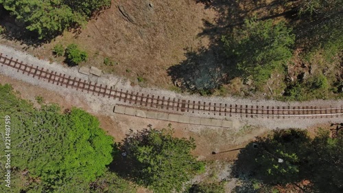 Aerial top view of winding narrow gauge railway curving through green forest in Mokra Gora, Serbia. Small station in mountain, 4k