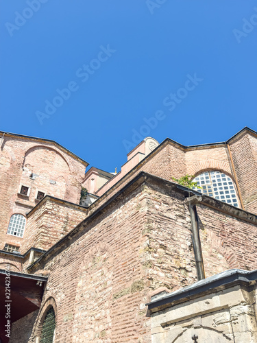 Historic stone architecture of a Byzantine building under a clear blue sky with intricate windows and detailed brickwork visible