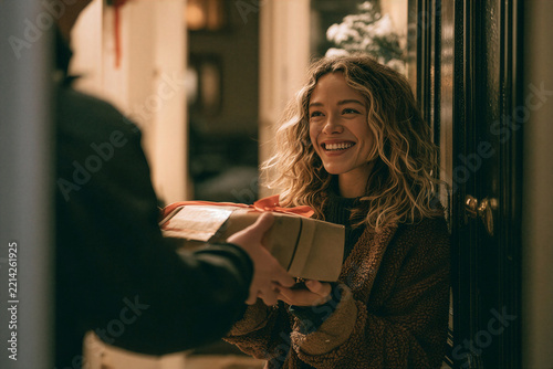 Man handing a wrapped gift box to a smiling woman at her doorway shown in vivid detail