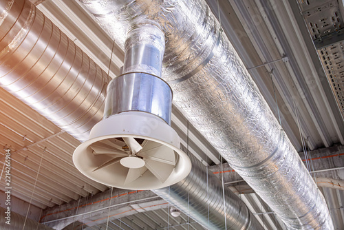 Industrial air conditioning system featuring metal ducts and a large fan, providing climate control and airflow in a modern building