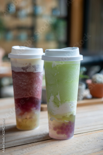 A glass of green grape tea with bubble pop, and a grape tea with chewy jelly, with cheese foam