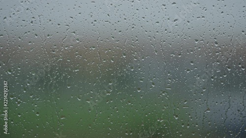 Rain drop hitting window glass and sliding down