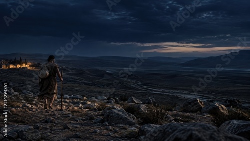 Man with staff and bundle walks across rocky wilderness toward a distant settlement. Cains exile in Genesis. Biblical story of banishment and wandering. Journey and survival concept.
