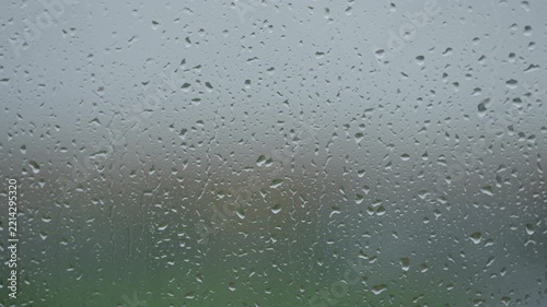 Rain drop hitting window glass and sliding down