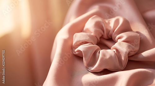 Pink silk scrunchie on soft fabric background