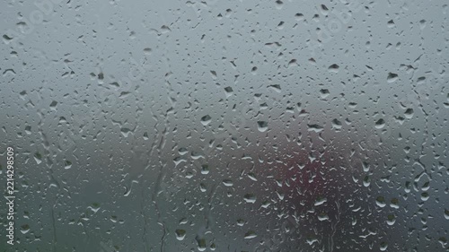 Rain drop hitting window glass and sliding down