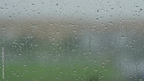 Rain drop hitting window glass and sliding down
