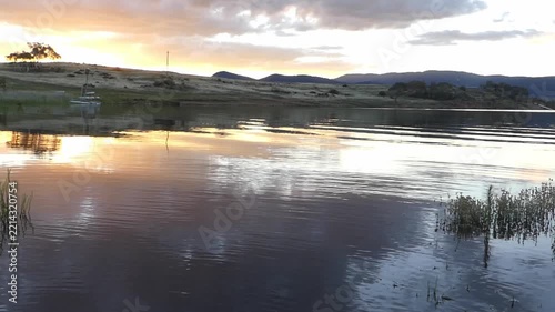 Calm alpine lake sunset with boat anchored ripples on the water