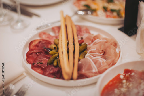 Delicious spread of cured meats and pickles on a beautiful white plate