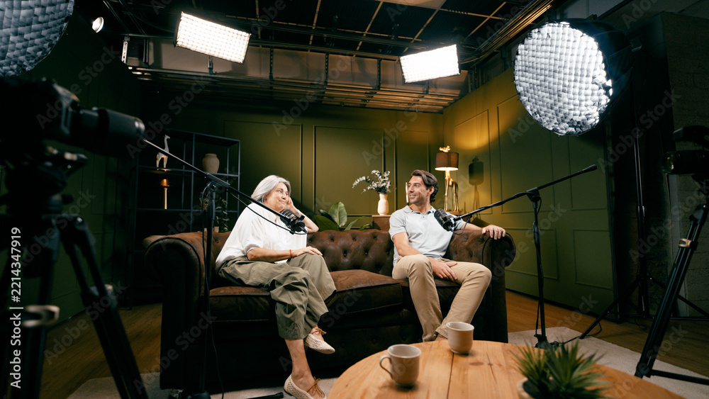 Obraz premium Two people creating a podcast, broadcasting their interview in a professional studio setting with microphones and camera