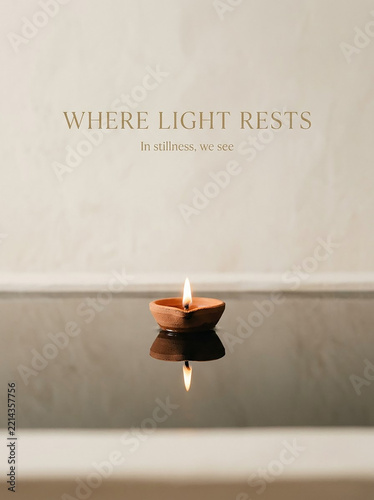 Diya floating on reflective water surface with inspirational text for