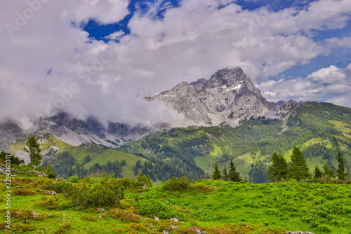 Panoramic alpine landscape around Salzburg, Austria, featuring majestic snow-covered peaks, rugged mountain ridges, green foothills, forested slopes, and picturesque valleys of Austria