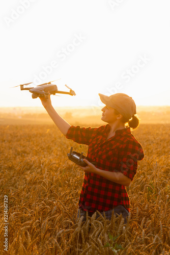 Woman farmer with drone on a wheat field. Smart farming and precision agriculture.